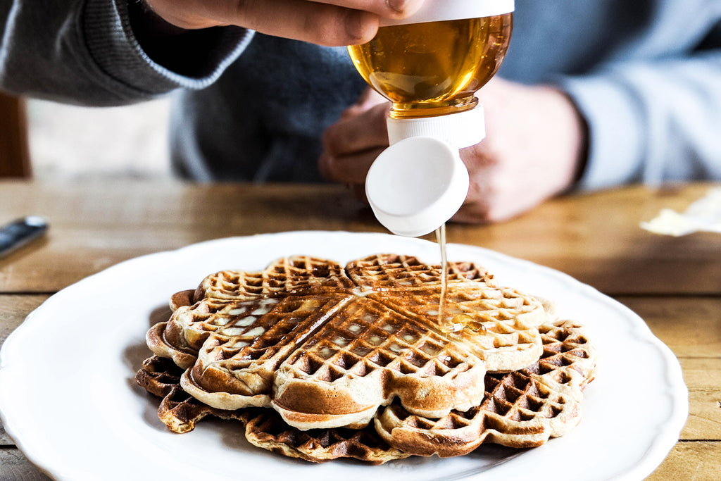 ShortHive Australian Caramel Salted Honey being drizzled by a person onto waffles
