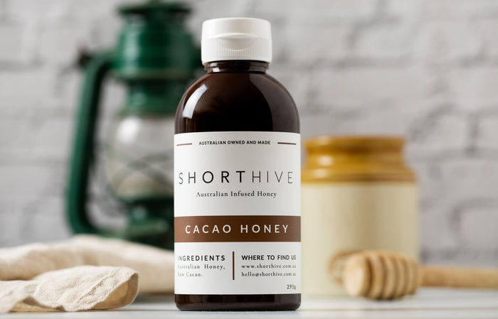 ShortHive Chocolate (Cacao) Infused Australian Honey bottle. Up-close of bottle with styled background out of focus