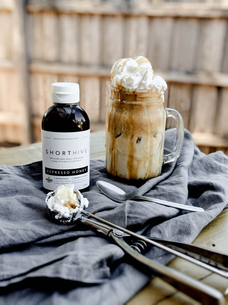 ShortHive Espresso (Coffee) Infused Australian Honey bottle sitting beside an indulgent latte with ice-cream on top drizzled with more coffee/espresso honey 
