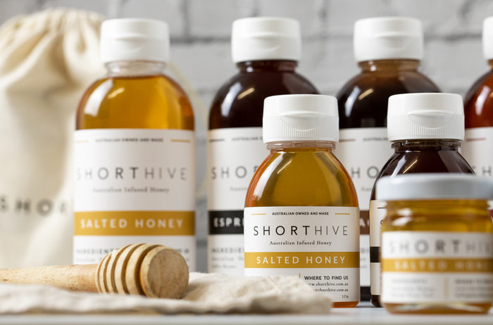 Styled ShortHive Collection pictured with small and large bottles with Salted Caramel Honey and Espresso Coffee Honey.