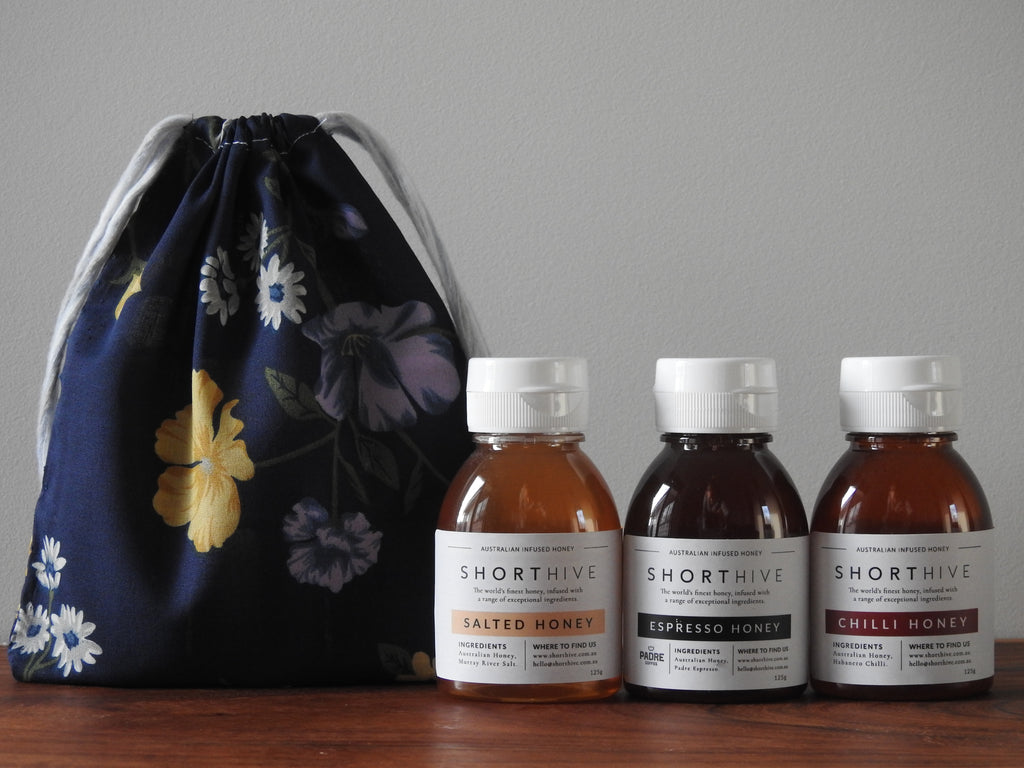 125g of bottles of Salted (caramel) honey, Espresso (coffee) honey, Chilli (spicy) honey pictured with a flower patterned gift bag.