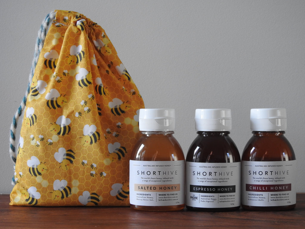 125g of bottles of Salted (caramel) honey, Espresso (coffee) honey, Chilli (spicy) honey pictured with a yellow bee patterned gift bag.