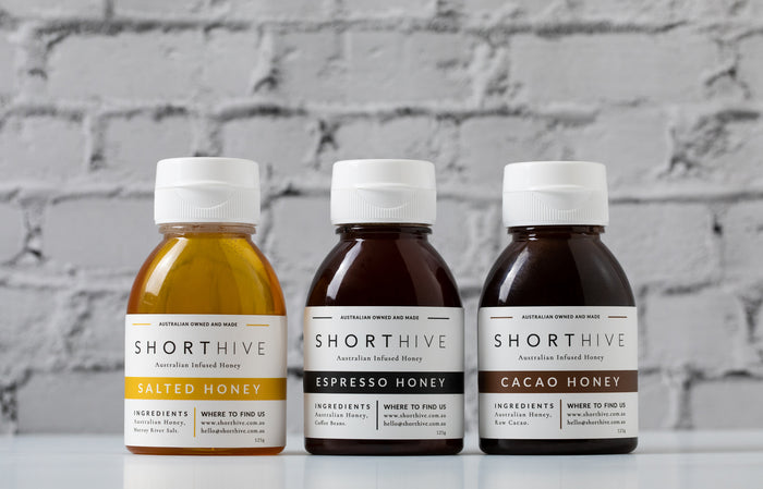 ShortHive Australian Infused Honey 125g bottles lines up on white background. Salted Caramel Honey, Coffee Honey, Chocolate Honey, Chilli (habanero) Honey.